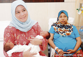 Tengku Puan Pahang Tunku Azizah Aminah Maimunah Iskandariah (left) holding the the twin born to Zulkifli Sari and Roslah Sanusi.